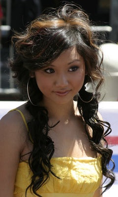 In a Yellow blouse Brenda Song watches intently